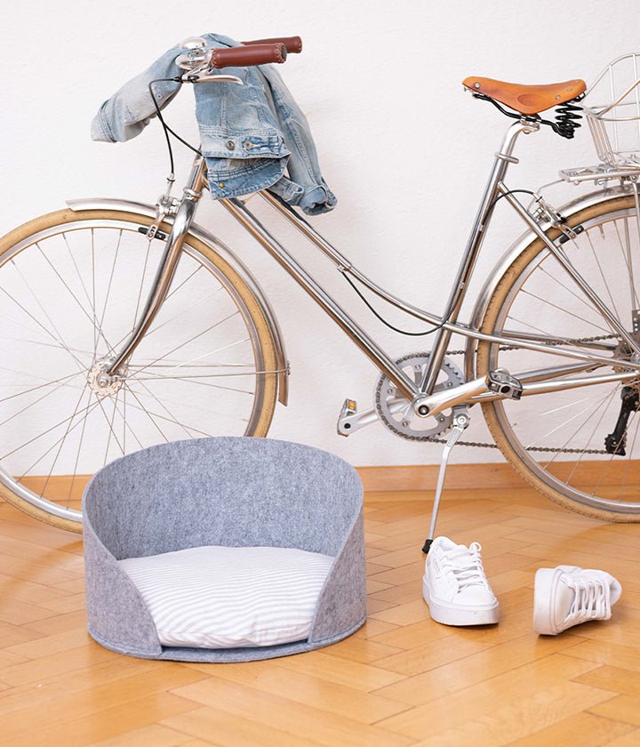 Lit pour animaux en feutre gris clair avec bords incurvés et coussin rayé